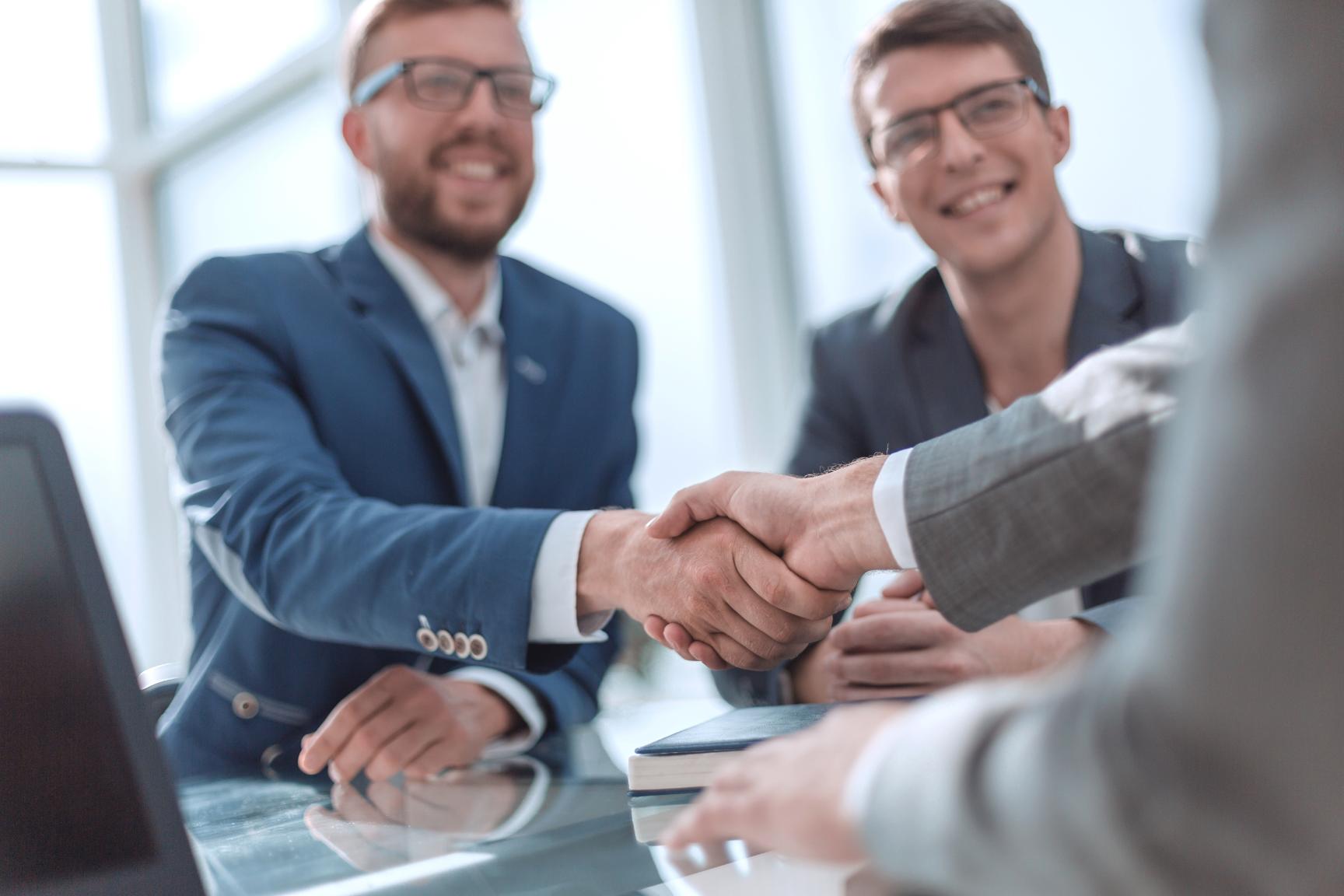 Client and representative shaking hands at a conference table