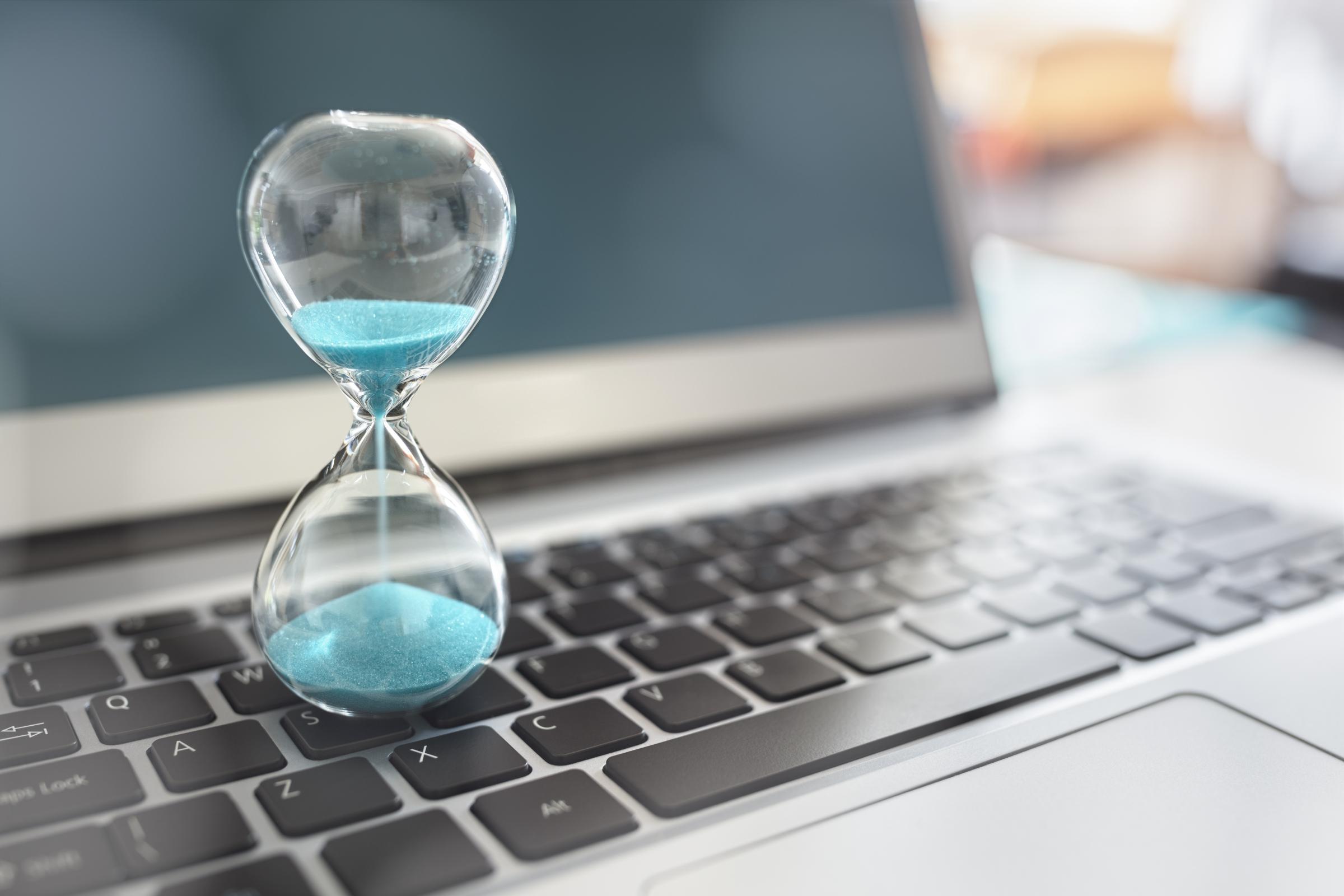 Hourglass sitting on a laptop counting down the time