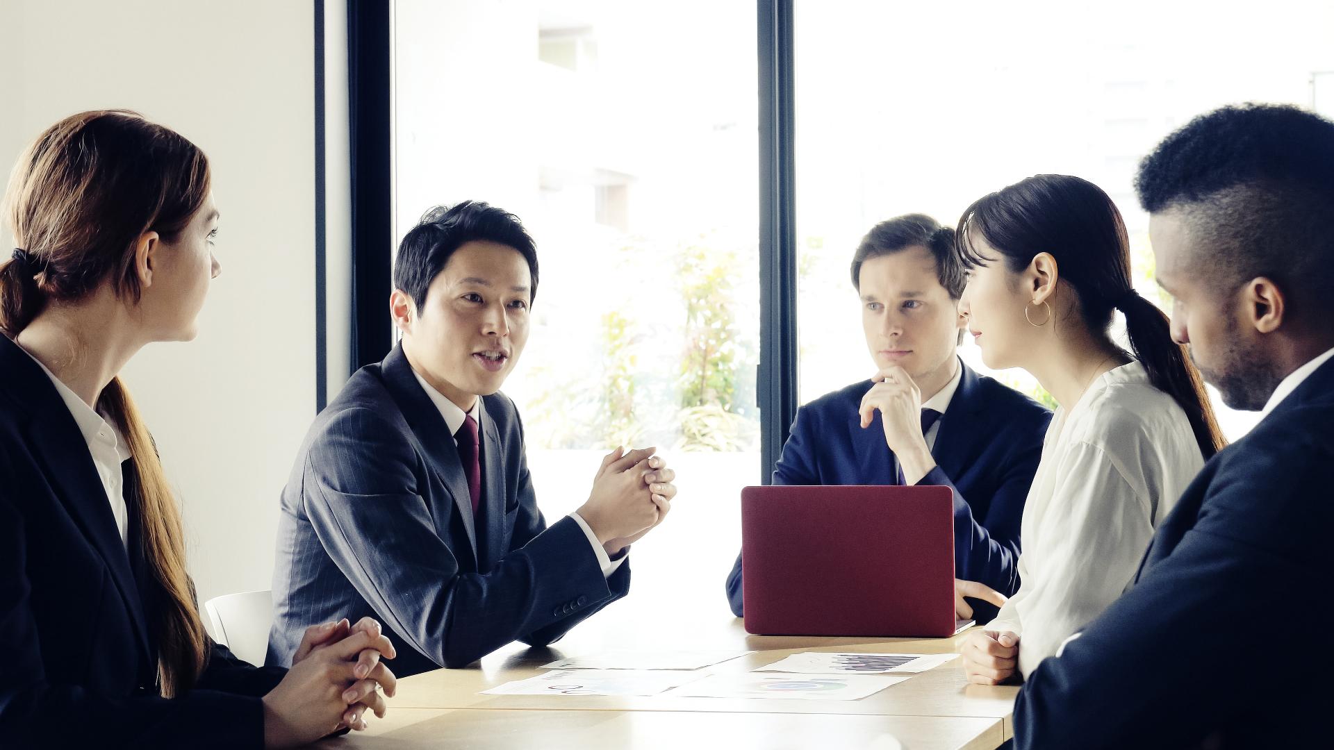 Group of business people sitting around conference table talking